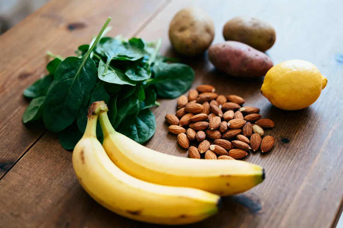 Bananes, épinards, pommes de terre, amandes et citron sur table en bois, vue rapprochée.