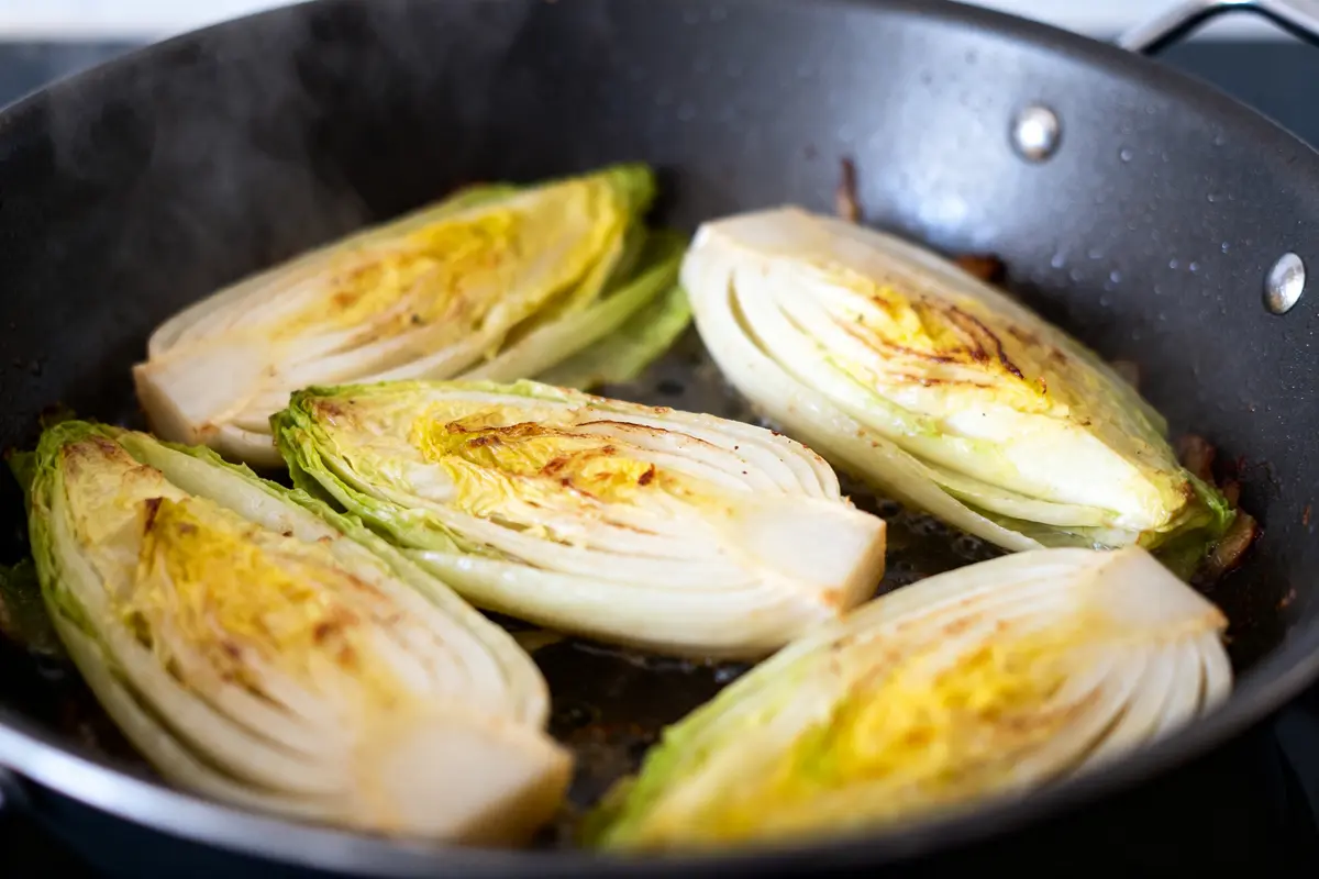 Endives à moitié cuites dans une poêle illustrant la cuisson de l'endive.
