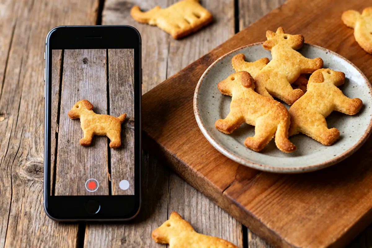 Téléphone affichant sablés animaux en forme de chien, assiette similaire à côté