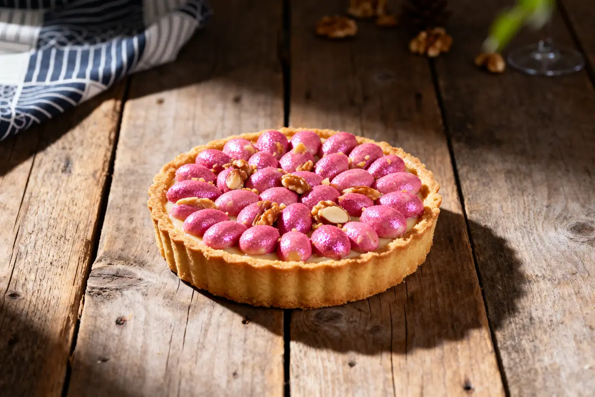 Tarte à la praline lyonnaise sur table rustique en bois avec garniture aux noix