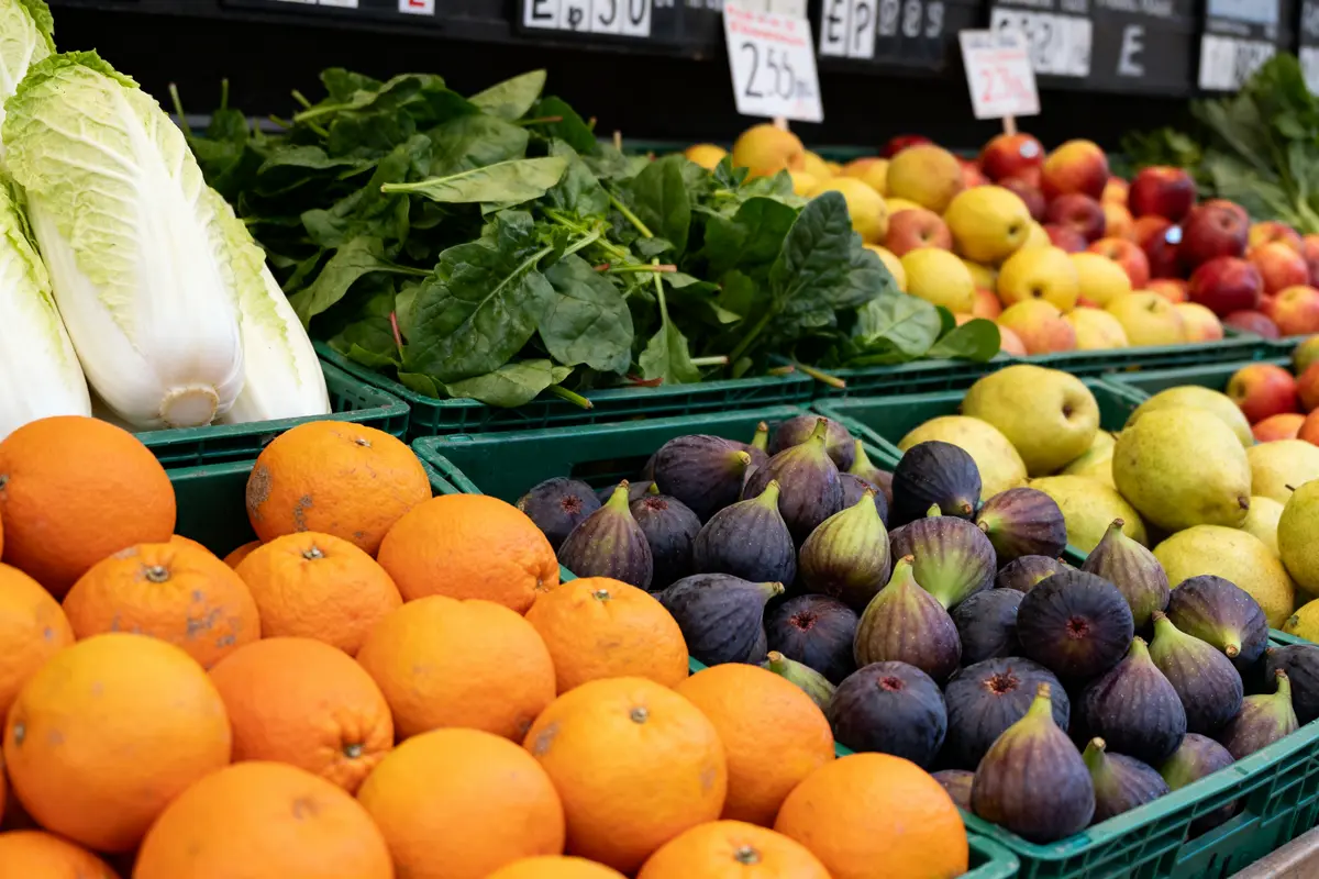 Belles oranges, figues, poires et légumes en E exposés sur un marché coloré